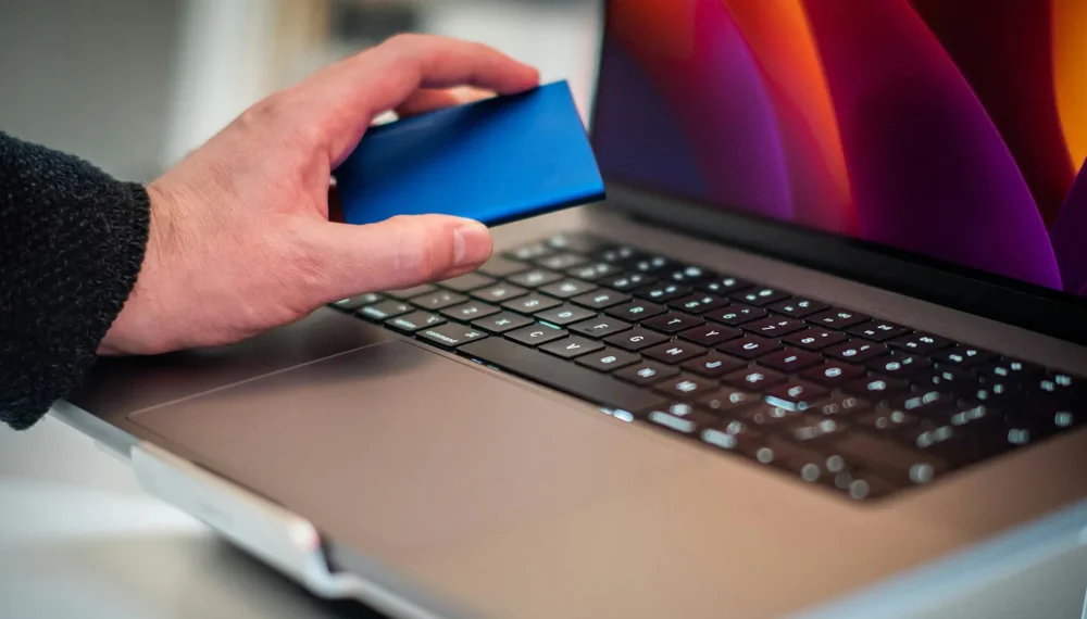man-hand-holding-disk-over-laptop
