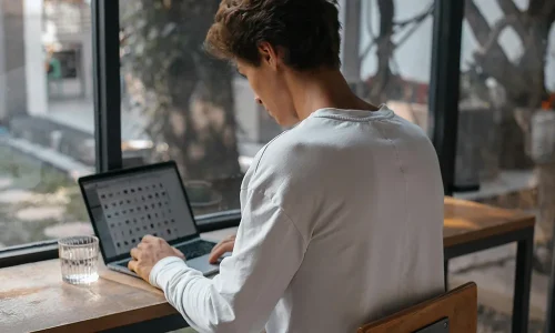 man-sitting-by-window-and-working-on-laptop