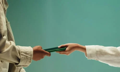 unrecognizable-hands-of-two-teenagers-holding-green-mobile-phone